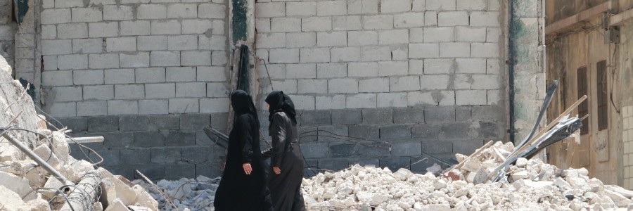 نساء يمشين في حي المعادي بين ركام القصف