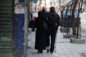 أمرأة تساعد زوجها على المشي في حي بستان القصر